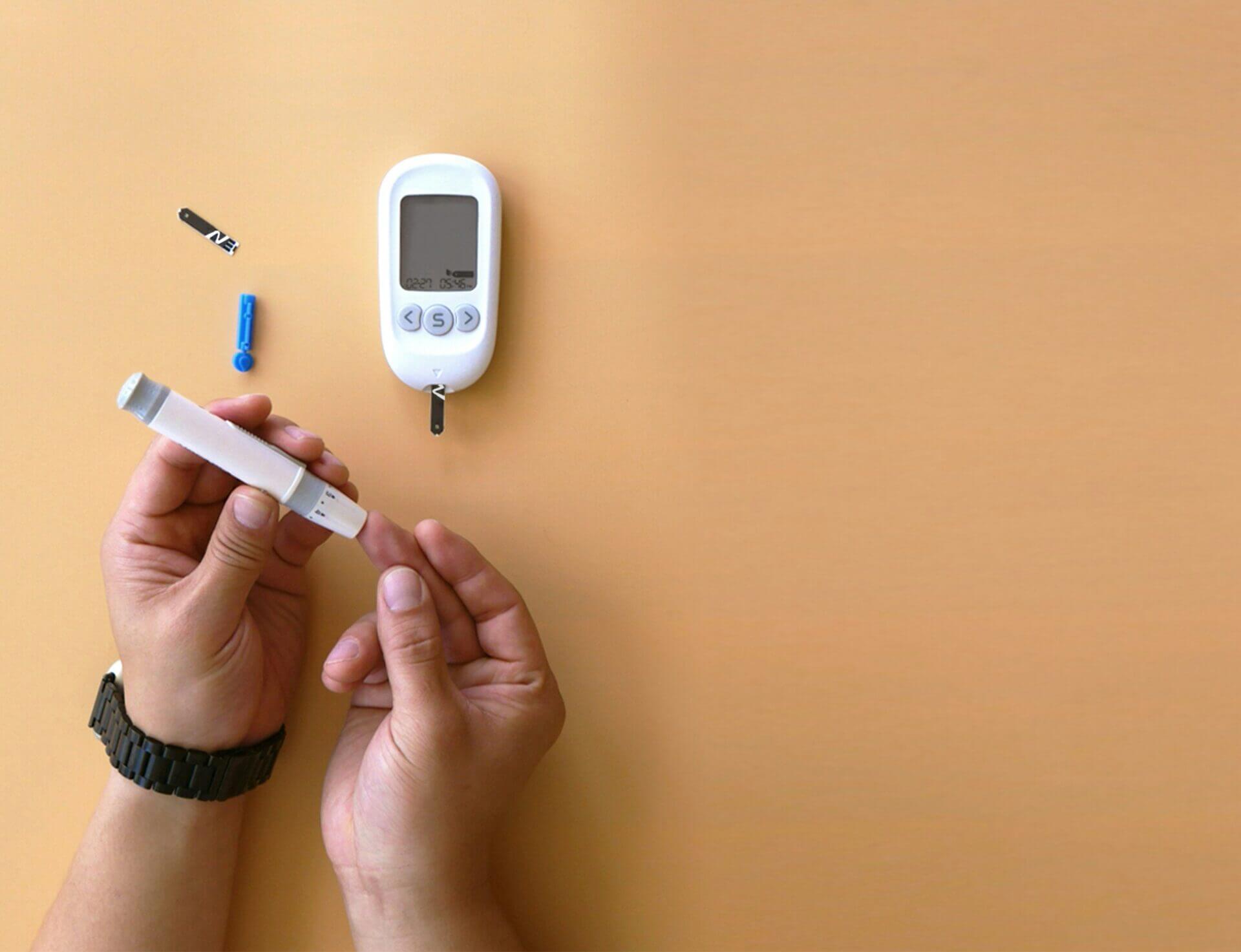 A person holding a glucose meter and a small electronic device for monitoring blood sugar levels.