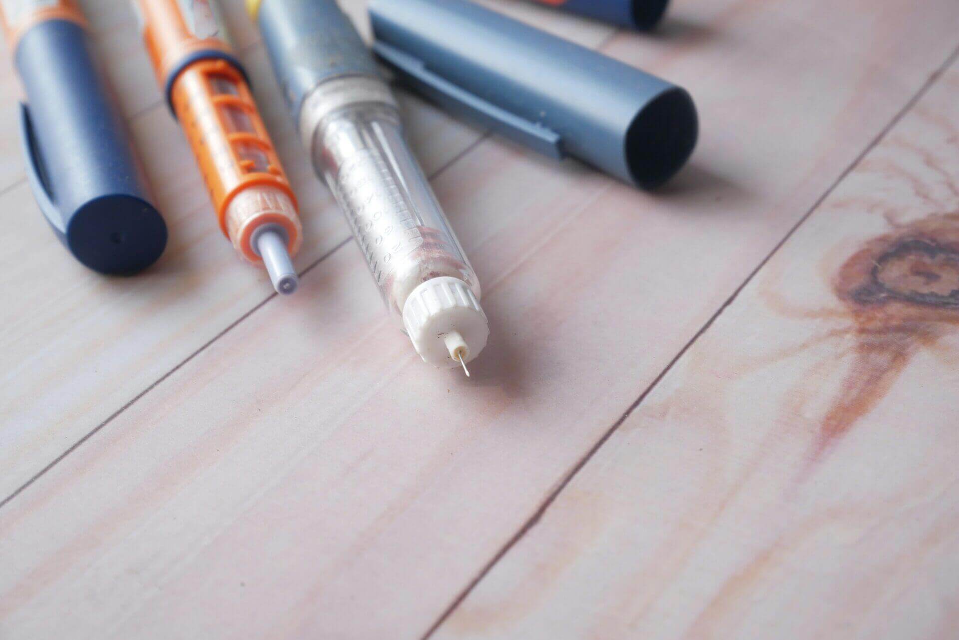 Insulin pens on wooden background, close-up